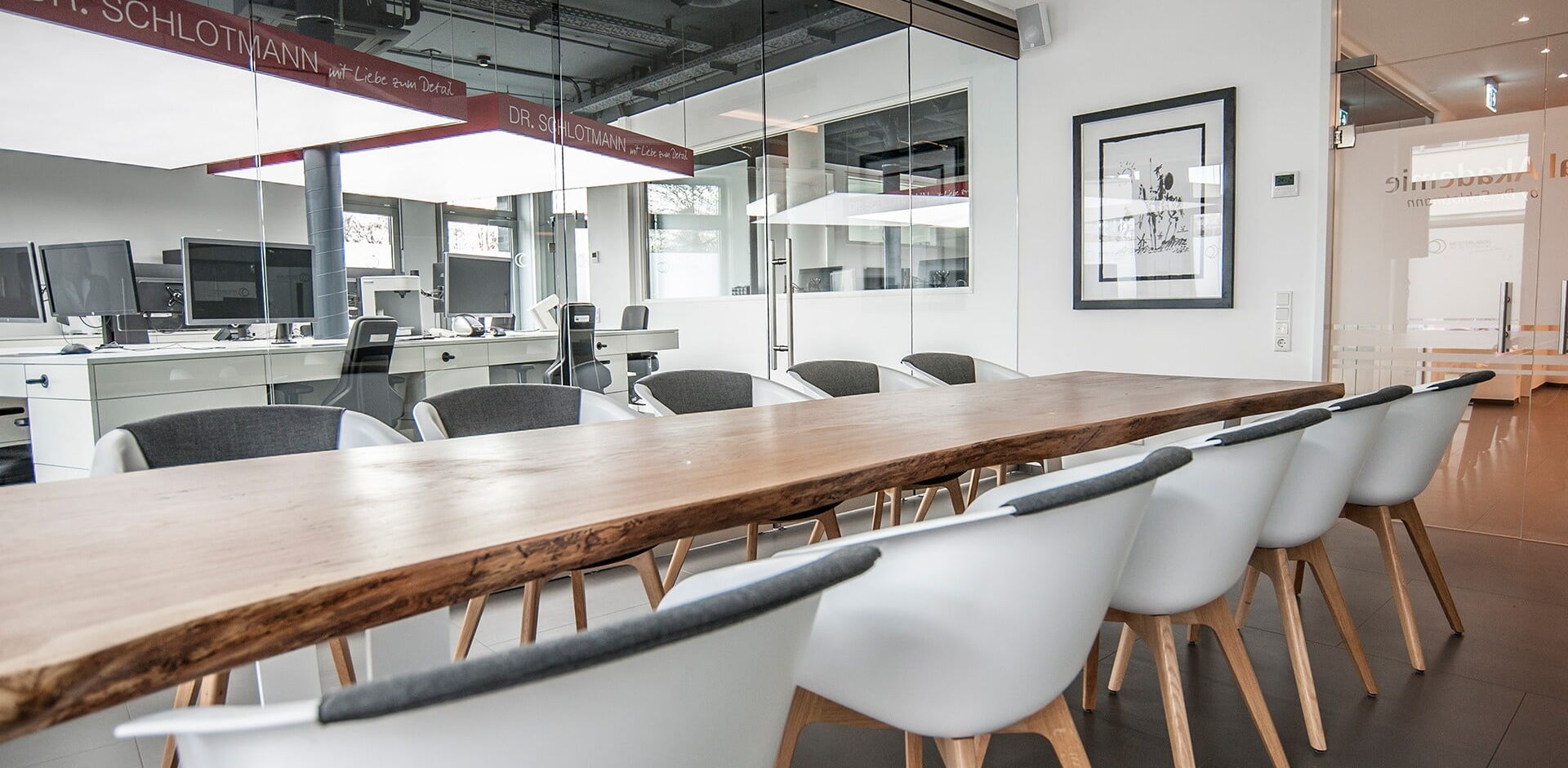 Konferenzraum mit langem Konferenztisch und großer Glaswand in einem Graußraumbüro.