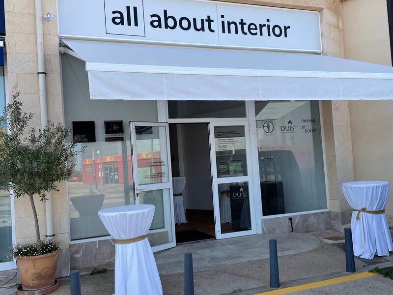 Ein Ladeneingang mit offener Tür. Über dem Eingang hängt ein Schild mit der Beschriftung "all about interior".