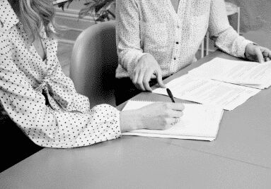 Zwei Personen sitzen am Tisch und bearbeiten gemeinsam Dokumente.