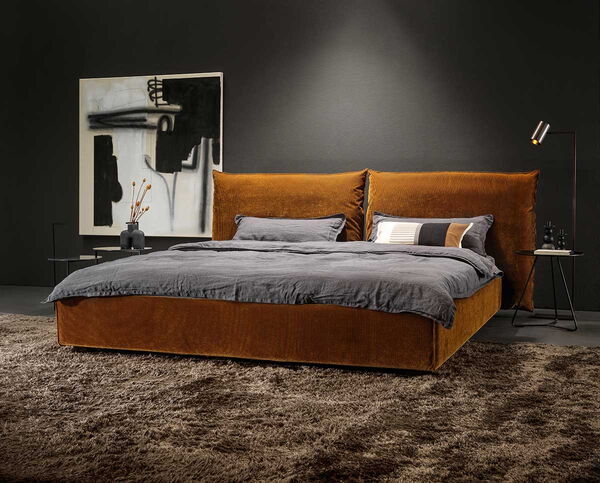 Braunes Bett vor schwarzer Wand