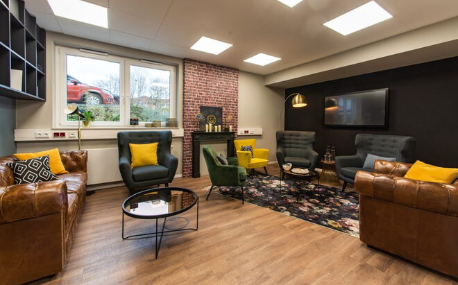 Wohnzimmer mit vielen Sesseln und belben Farbtupfern