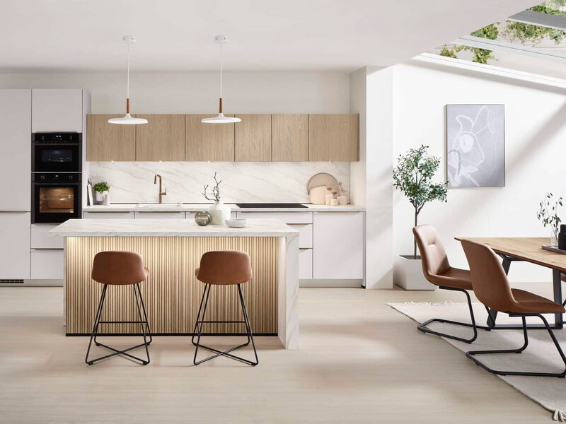 Offene Wohnküche mit Kochinsel, Esstisch und Stühlen in warmen Farbtönen, hell und einladend gestaltet.