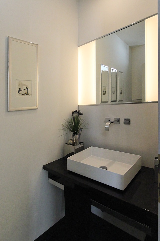 Kleines Badezimmer mit Waschtisch und beleuchtetem Spiegel